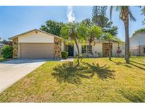 Charming home featuring stone accents, a well-maintained lawn, and decorative palm trees creating a welcoming curb appeal at 12838 Tallowood Dr, Riverview, FL 33579