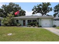 Single-story home featuring a well-maintained lawn and an attached garage at 1665 Grove St, Clearwater, FL 33755