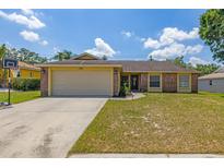 Charming single-story home showcasing a manicured lawn, a driveway, and an attached two-car garage at 1720 Fruitridge St, Brandon, FL 33510