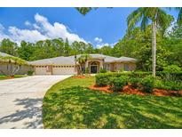 Well-maintained home featuring manicured landscaping, a lush lawn, and a three-car garage at 1877 Muirfield Way, Oldsmar, FL 34677
