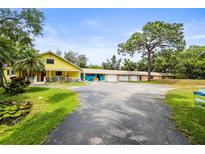 Wide view of a colorful home with a long driveway and mature trees at 2174 62Nd N St, Clearwater, FL 33760