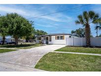 Charming single-story home featuring a well-manicured lawn, painted driveway, and tropical landscaping at 9097 Southern Comfort Dr, Largo, FL 33773