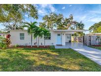 Charming single-story home featuring a light blue front door, palm trees, and well-manicured lawn at 10664 Starkey Rd, Seminole, FL 33777