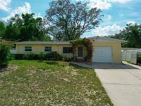 Charming single-story home with a well-manicured lawn and a flowering pergola over the front entrance at 10912 N 61St St, Temple Terrace, FL 33617