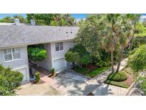 A two-story townhome with an attached garage, paved driveway, and mature trees and landscaping at 1211 W Horatio St # A, Tampa, FL 33606