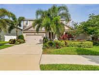 Charming two-story home featuring a well-manicured lawn, lush landscaping, and a two-car garage at 13118 Rain Lily Dr, Riverview, FL 33579