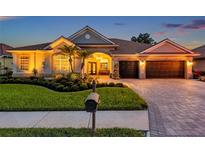 Stunning single-story home featuring lush landscaping and a paver driveway leading to a spacious three-car garage at 1617 El Pardo Dr, Trinity, FL 34655
