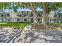 Charming townhouse with dormer windows, surrounded by mature trees and lush landscaping at 1710 Belleair Forest Dr # A, Belleair, FL 33756