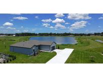 Stunning aerial view of a modern home with a long driveway, nestled beside a serene lake and lush green lawn at 2426 Hiers Rd, Dover, FL 33527