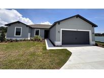 Charming single-story home featuring a two-car garage, well-maintained lawn, and neutral gray color palette at 2426 Hiers Rd, Dover, FL 33527