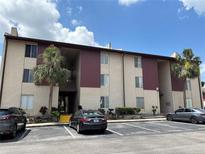 Three story condo building featuring stucco walls, palm trees and ample parking spaces at 3814 N Lake Dr # 65, Tampa, FL 33614