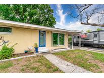 Charming home featuring a blue front door, well-maintained lawn, and carport with RV parking at 4411 W Bay Villa Ave, Tampa, FL 33611