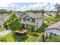 Stunning two-story home with manicured landscaping, mature trees, and charming front porch at 4496 Tatum Loop, Odessa, FL 33556