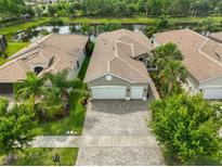 Aerial view of a lovely home with a well-maintained tile roof, lush landscaping, and picturesque lake views at 4830 Grand Banks Dr, Wimauma, FL 33598