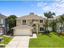 Charming two-story home featuring manicured lawn, an attached garage, and lush tropical landscaping at 4852 Trinidad Dr, Land O Lakes, FL 34639