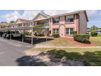 Two-story condo building featuring a covered carport, brick accents, and well-maintained landscaping at 6334 Spring Flower Dr # 24, New Port Richey, FL 34653