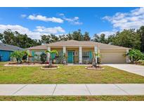 Charming single-story home with a well-manicured lawn, vibrant turquoise accents, and a welcoming front porch at 6724 Clair Shore Dr, Apollo Beach, FL 33572
