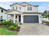 Charming two-story home featuring a gray garage door, a welcoming front porch, and well-maintained landscaping at 718 W Kentucky Ave, Tampa, FL 33603