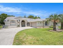 Well-maintained front yard with a circular driveway and manicured landscaping that enhance the home's curb appeal at 14181 Cornewall Ln, Spring Hill, FL 34609