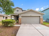 Charming gray two-story home with a two-car garage, stone accents, manicured landscaping, and concrete driveway at 18320 Snowdonia Dr, Land O Lakes, FL 34638