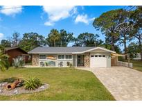 Charming single-story home featuring a well-maintained lawn, stone accents and an attached one car garage at 2048 Douglas Ave, Dunedin, FL 34698