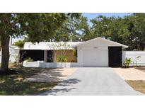 Charming single-story home featuring lush landscaping, a brick driveway, and a white exterior at 2551 12Th St, Englewood, FL 34224