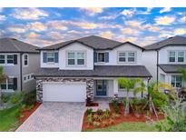 Two-story home featuring a brick-accented garage, well-manicured landscaping, and a contrasting front door at 3063 Marine Grass Dr, Wimauma, FL 33598