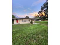 Charming single-story home featuring a red door, and a well-manicured front yard at 33516 Arthur Dr, Wesley Chapel, FL 33543