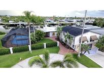 Stunning waterfront home with a screened pool, lush landscaping, and circular driveway at 3654 Corsair Ct, New Port Richey, FL 34652