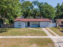 Charming single-story home features a manicured lawn, complemented by lush green trees at 4706 E Sligh Ave, Tampa, FL 33610