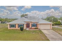 Inviting single-story home featuring a metal roof, double door entry, and attached two car garage at 5432 Queen Ave, Spring Hill, FL 34609