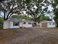Charming home with white siding, black shutters, metal roof, and detached garage at 5535 Peach Ave, Seffner, FL 33584