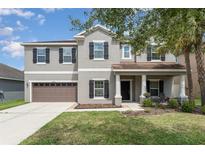 Charming two-story home with well-manicured lawn, covered porch with pillars and an attached two-car garage at 11206 Coventry Grove Cir, Lithia, FL 33547
