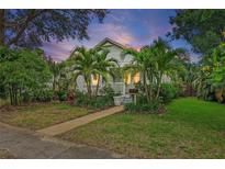 Charming home with mature tropical landscaping, lush green lawn and a welcoming walkway leading to the front porch at 1211 14Th N St, St Petersburg, FL 33705
