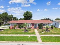 Charming single-story home featuring a well-maintained lawn and mature landscaping under a sunny sky at 1436 Santa Clara Dr, Dunedin, FL 34698