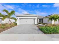 Charming single-story home with a paver driveway, two-car garage and well-maintained landscaping with palm trees at 17881 Star Ruby Pl, Nokomis, FL 34275