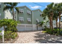 Inviting two-story home featuring a brick driveway, two-car garage and lush landscaping at 215 18Th Ave, Indian Rocks Beach, FL 33785