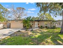 Charming single-story home with manicured lawn, complemented by lush landscaping and mature trees at 310 55Th S Ave, St Petersburg, FL 33705