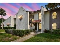 Inviting condo exterior with stucco walls, red roof tiles, manicured landscaping and warm accent lighting at dusk at 3505 Tarpon Woods Blvd # P404, Palm Harbor, FL 34685