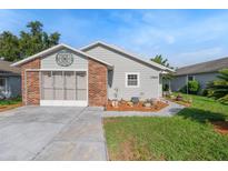 Charming single story home with brick accent, screened garage, colorful landscaping, and well maintained lawn at 37420 Teaberry Loop, Zephyrhills, FL 33542