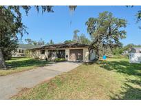 Charming single-story home featuring a driveway, attached garage, and mature trees at 4221 Burrows Rd, Zephyrhills, FL 33542