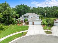 Charming two-story home with a three-car garage, lush landscaping, and a welcoming front yard on a cul-de-sac at 6127 Cezanne Ave, Lutz, FL 33558