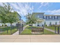 Camellia Square Townhomes with well-manicured lawns are framed by wrought iron fences and lush trees under a bright sky at 6619 S Manhattan Ave # 1, Tampa, FL 33616