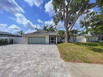 Charming single-story home with a well-maintained lawn and a patterned brick driveway on a sunny day at 9580 130Th Ave, Largo, FL 33773