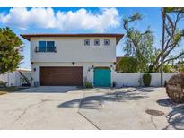 Two-story home featuring a brown garage door, turquoise front door and balcony on a bright day at 11285 8Th E St, Treasure Island, FL 33706