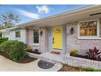 Inviting front entrance showcasing a vibrant yellow door, brick accents, and manicured landscaping at 1470 Serpentine S Dr, St Petersburg, FL 33705