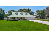 Charming home with a light green roof, lush front lawn and a spacious three car garage at 1914 Henley Rd, Lutz, FL 33558