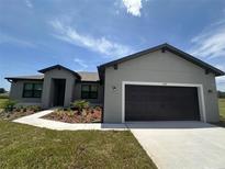 Charming single-story home with a dark garage door, complemented by a manicured lawn and blue sky at 2330 Hiers Rd, Dover, FL 33527