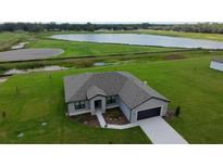 Aerial view of a modern home with a well-manicured lawn, a lake, and a dark roof at 2330 Hiers Rd, Dover, FL 33527