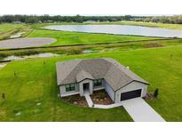 A charming single-story home boasts a well-manicured lawn and a serene lake view, creating an idyllic setting at 2402 Hiers Rd, Dover, FL 33527